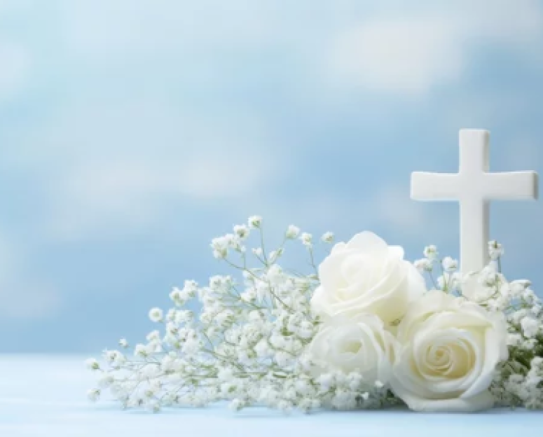 white crucifix and white roses and baby breath at it base with light blue whispy cloud sky background